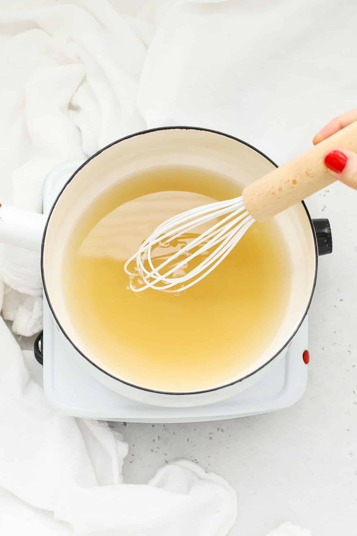 Dissolving sugar in water in a white saucepan