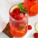 Two glasses of homemade raspberry lemonade with fresh raspberries, fresh mint, and lemon slices