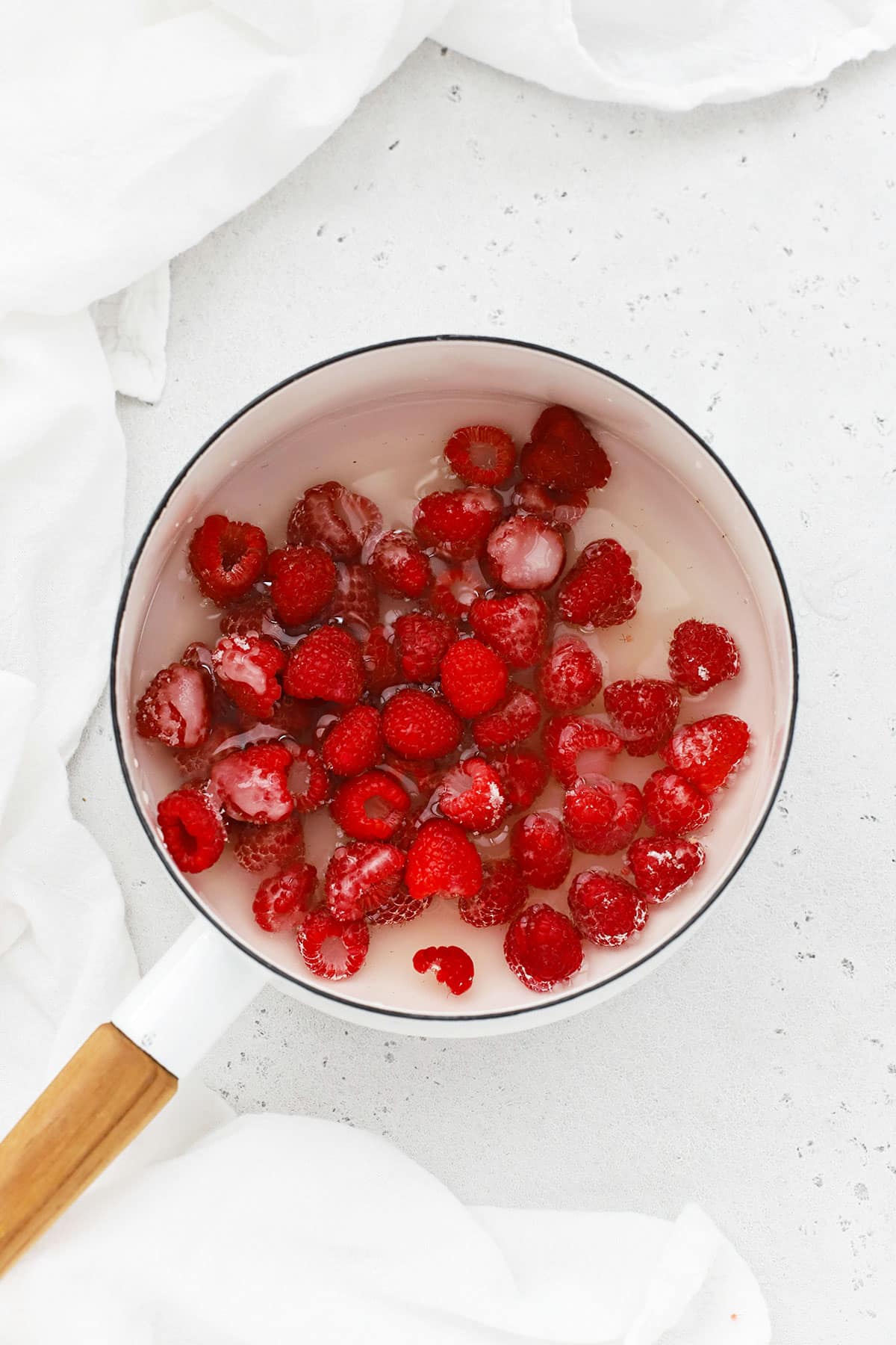 raspberries, sugar, and water in a white pan