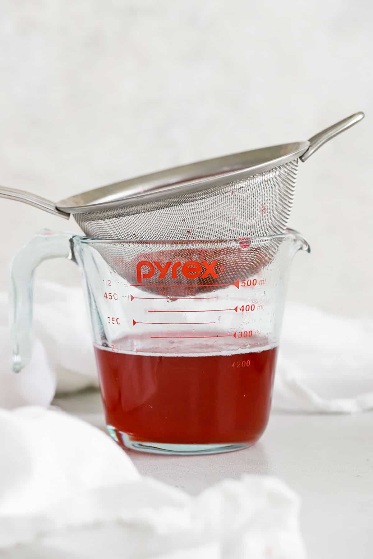 straining raspberry syrup for making lemonade