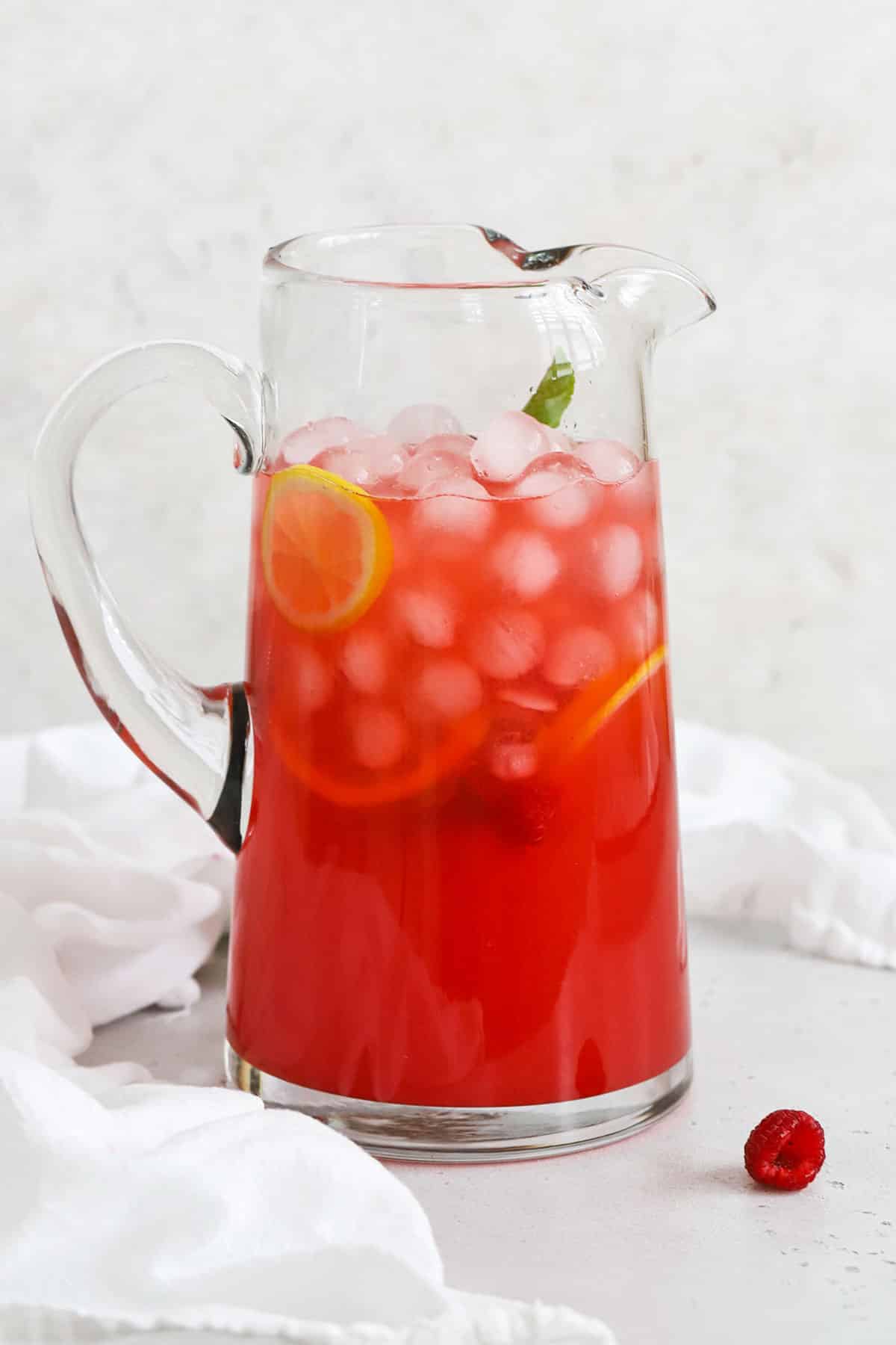 A glass pitcher of bright pink raspberry lemonade