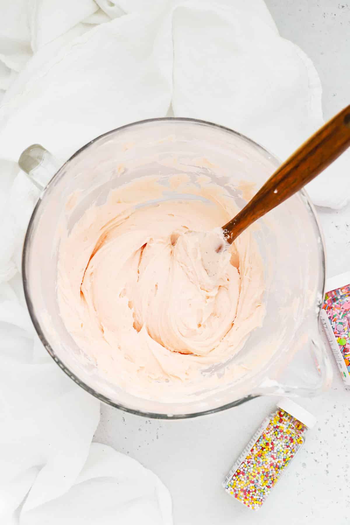 Fluffy pink frosting in a glass mixing bowl