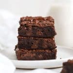 three fudgy gluten-free vegan brownies stacked on a white plate