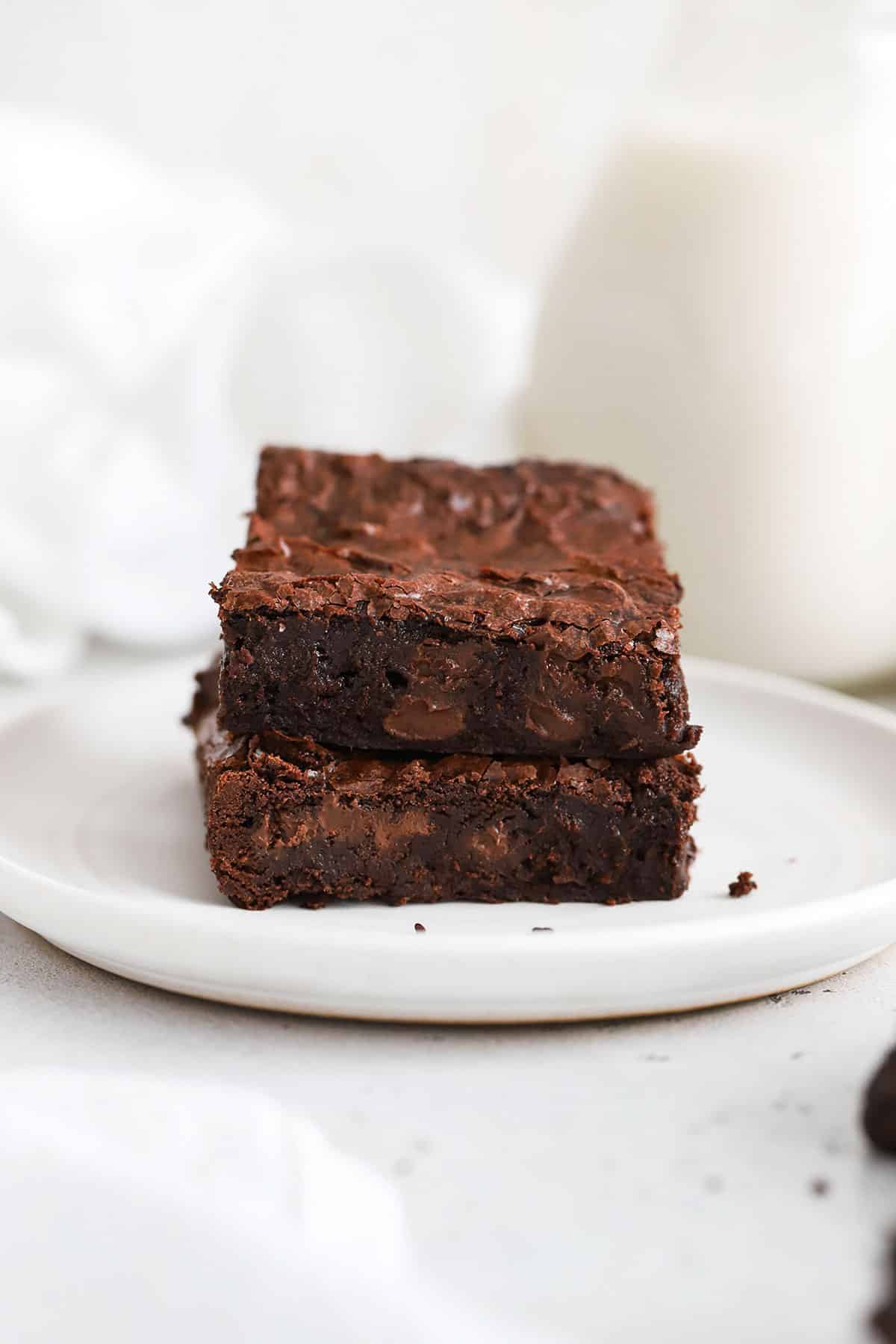 two fudgy brownies stacked on a white plate