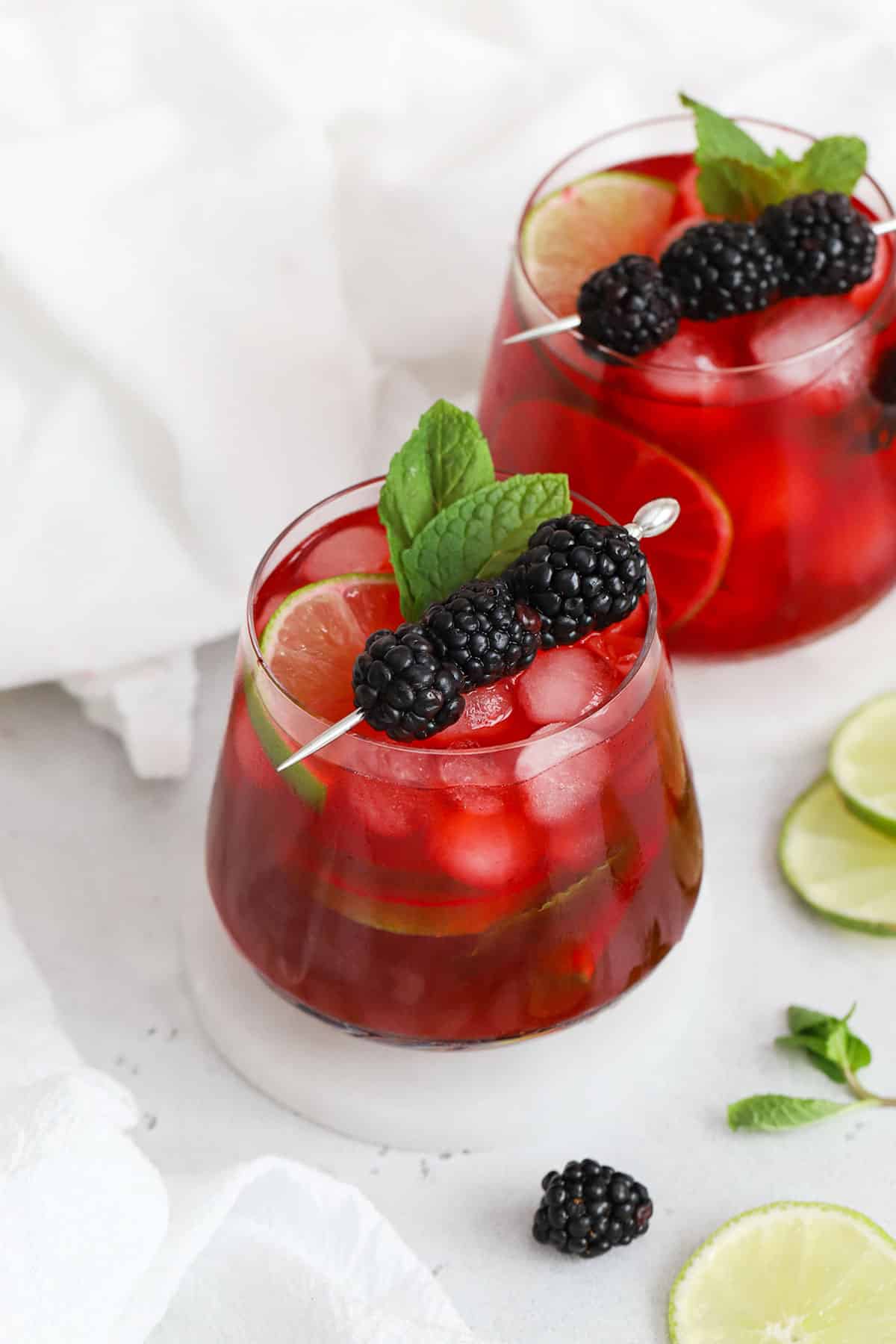 two glasses of blackberry limeade on white coasters