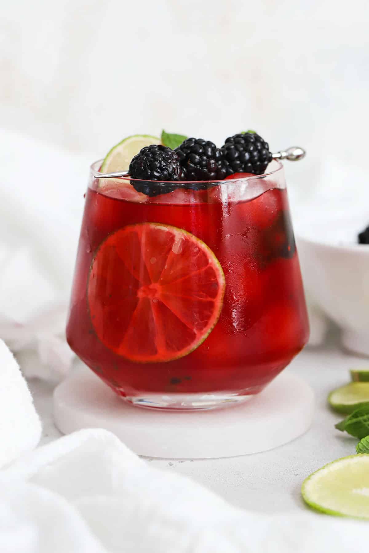 short glass of blackberry limeade garnished with fresh mint and blackberries