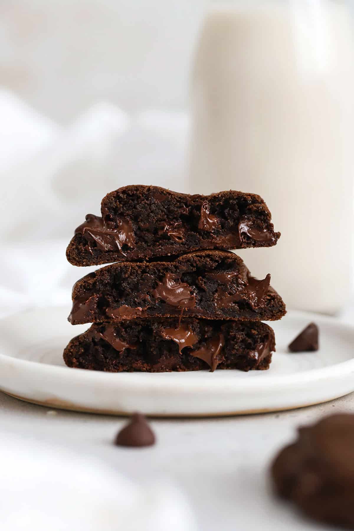 three gluten-free chocolate chocolate chip cookies stacked on a white plate
