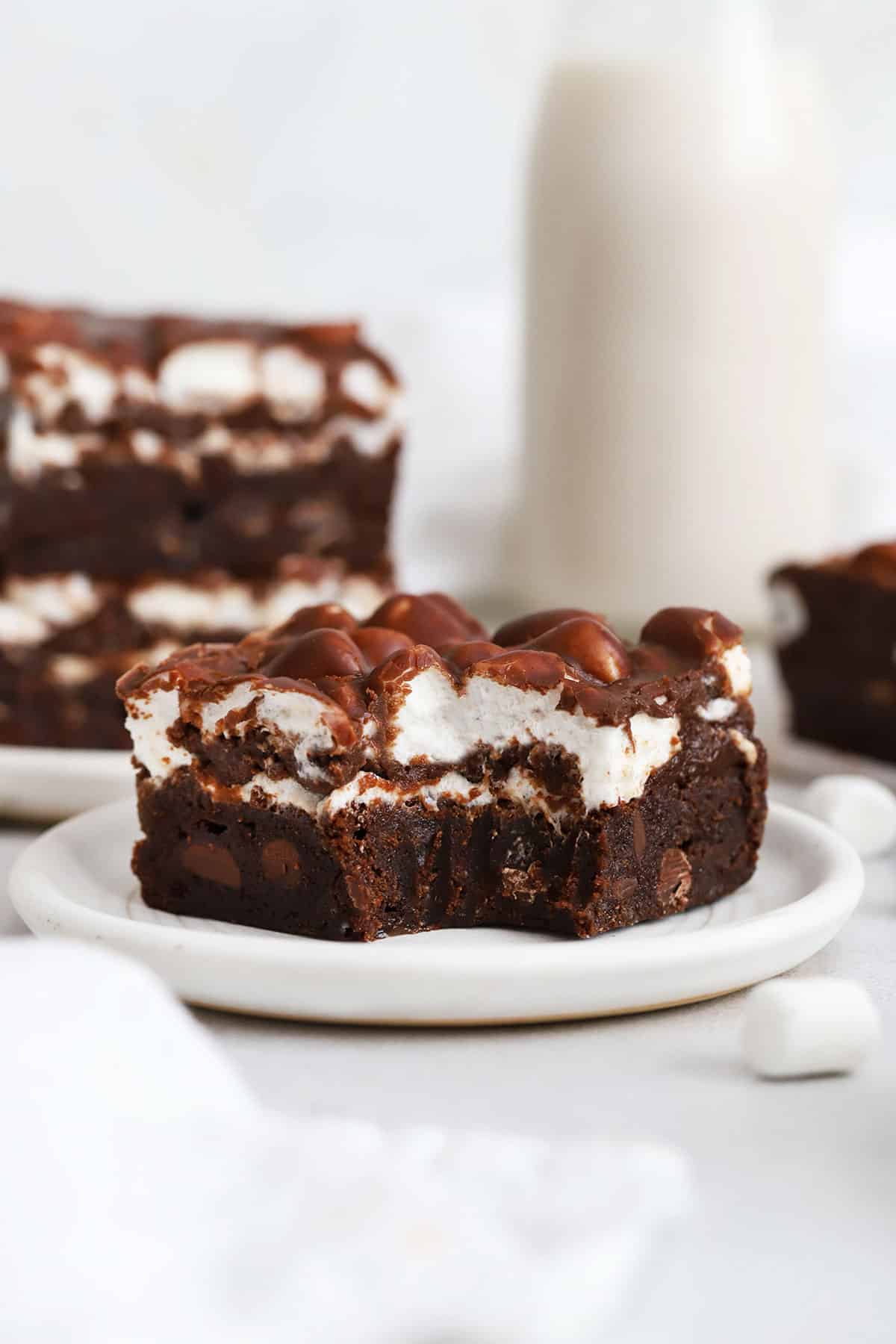 a gluten-free marshmallow brownie on a plate with a bite taken out of it