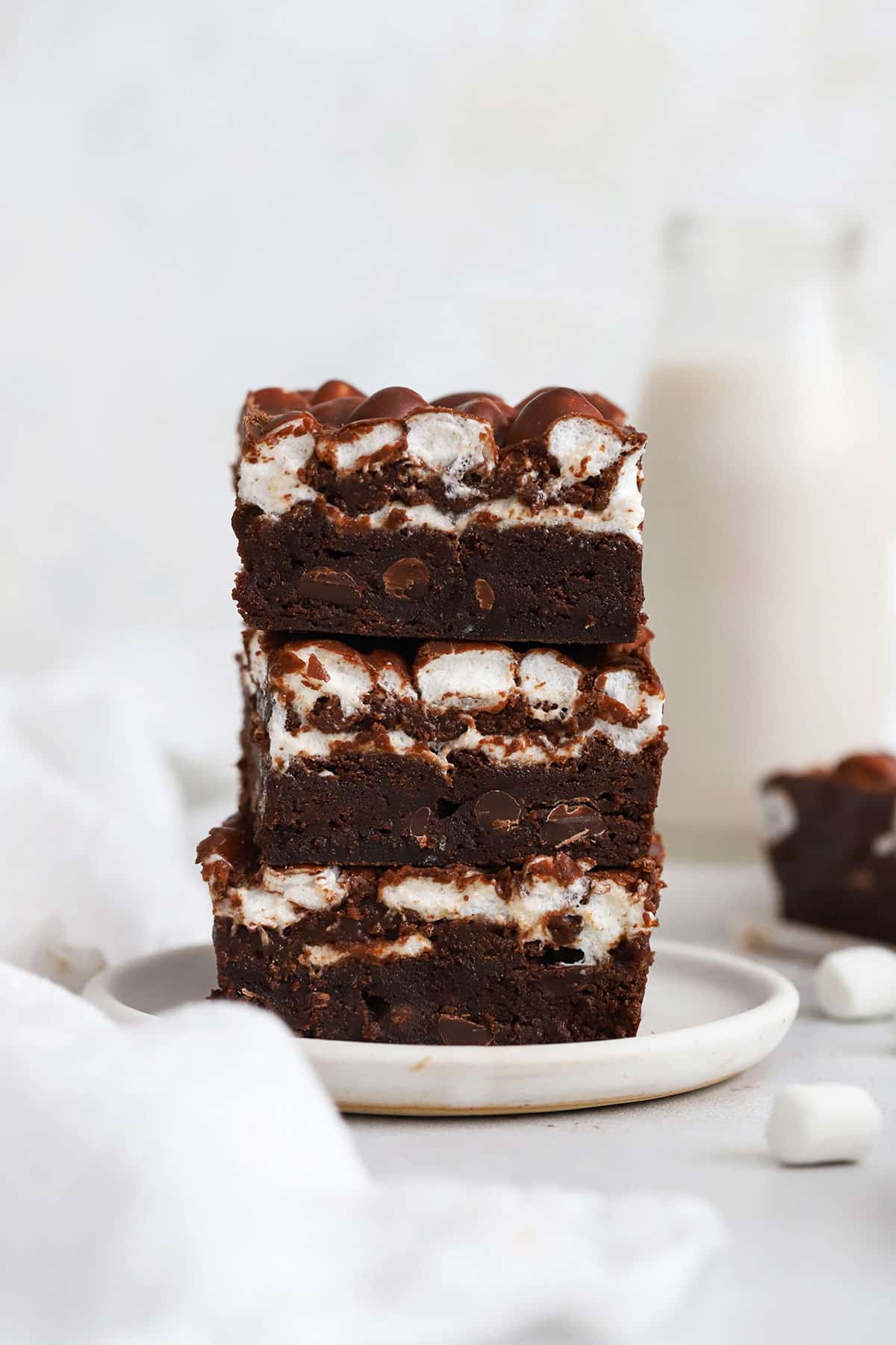 three gluten-free marshmallow brownies stacked on a plate