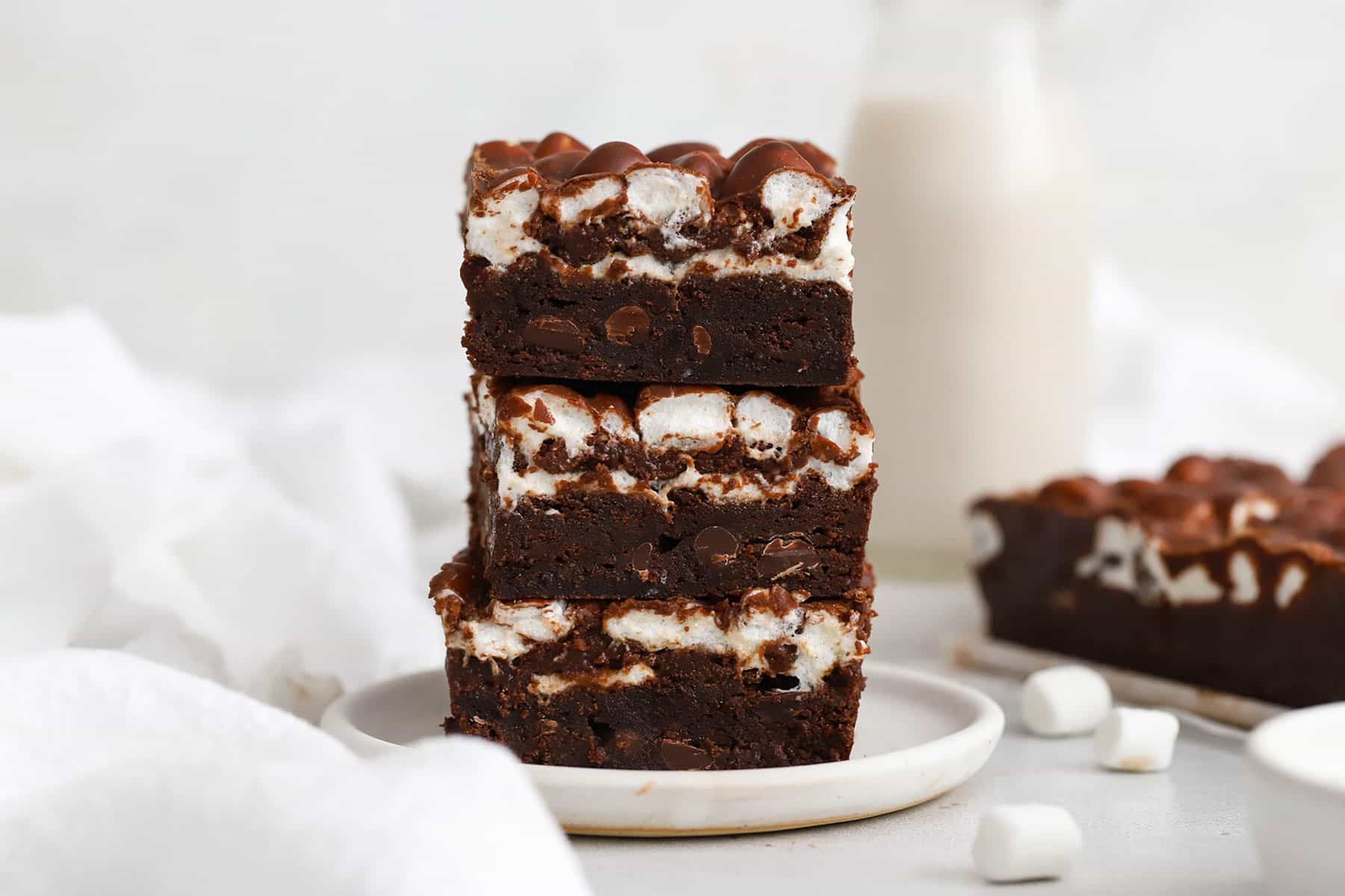 three gluten-free marshmallow brownies stacked on a plate