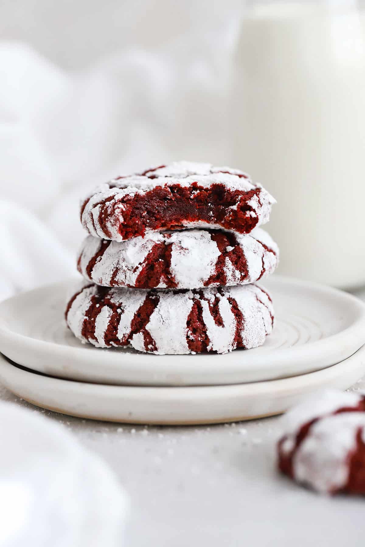 red velvet crinkle cookies stacked on white plates