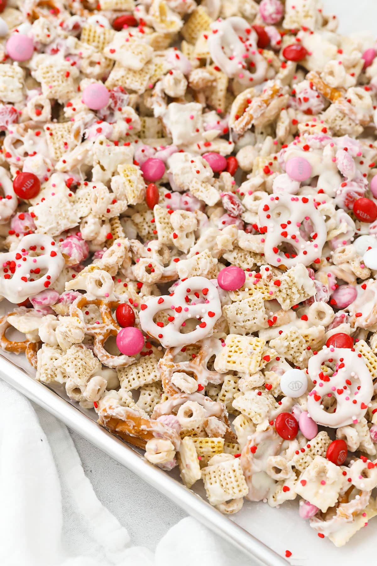 Spreading Valentines snack mix on a baking sheet