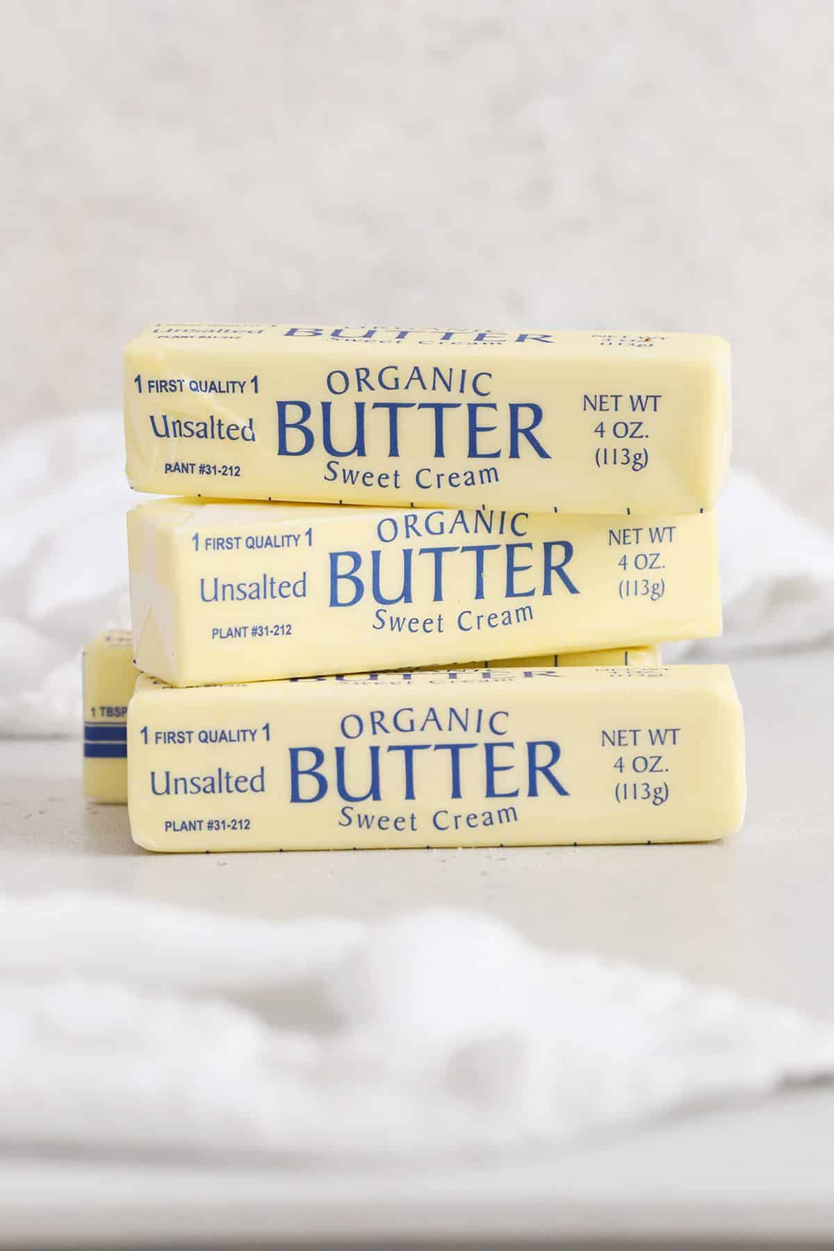 Four sticks of butter stacked on a white background