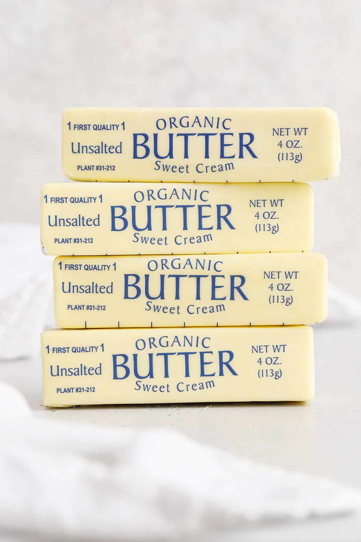 Four sticks of butter stacked on a white background