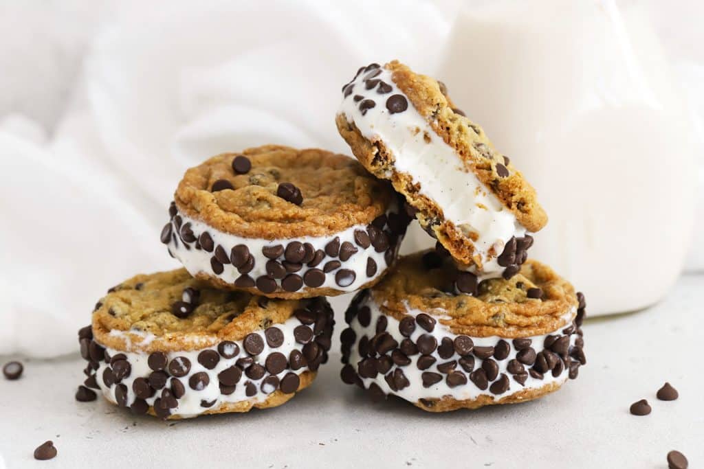 gluten-free chocolate chip cookie ice cream sandwiches stacked on a white background