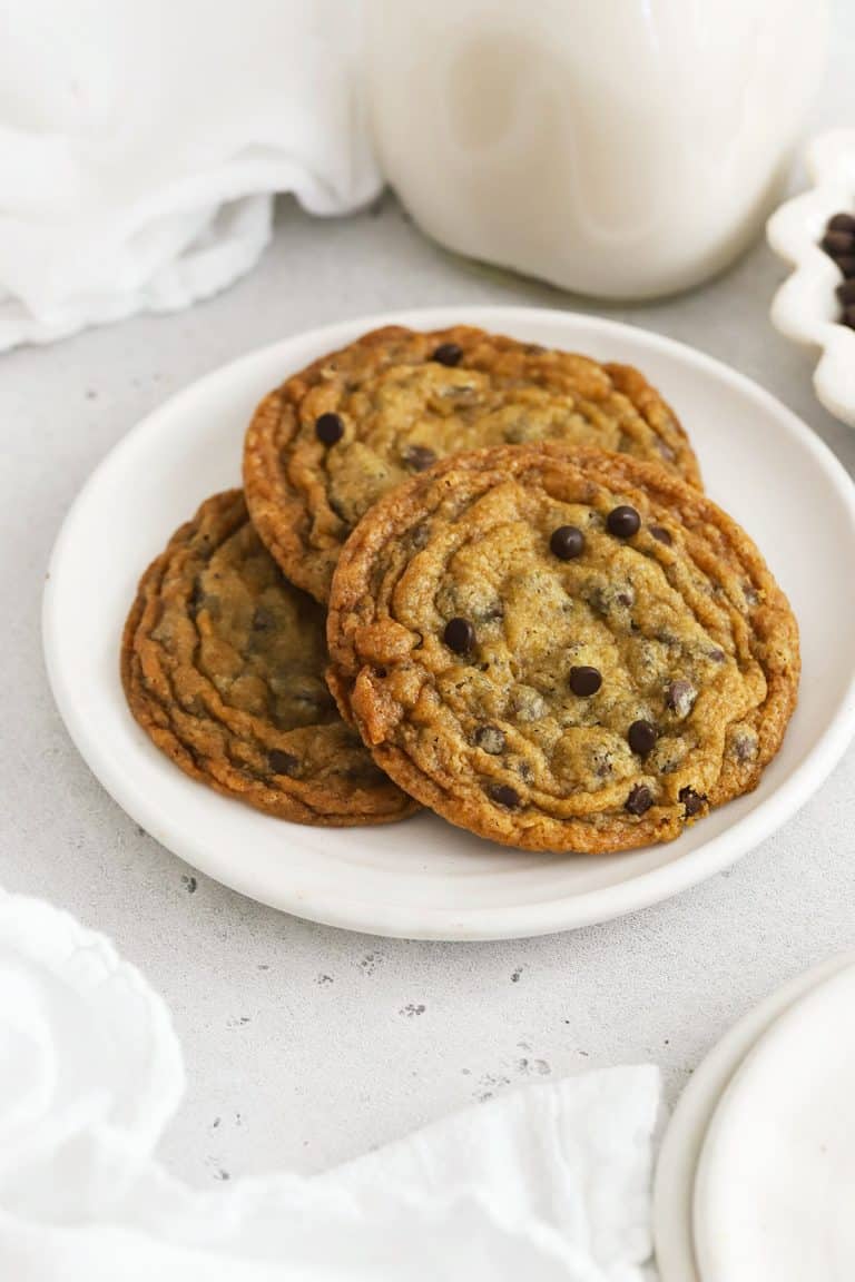Three crisp gluten-free chocolate chip cookies on a white plate
