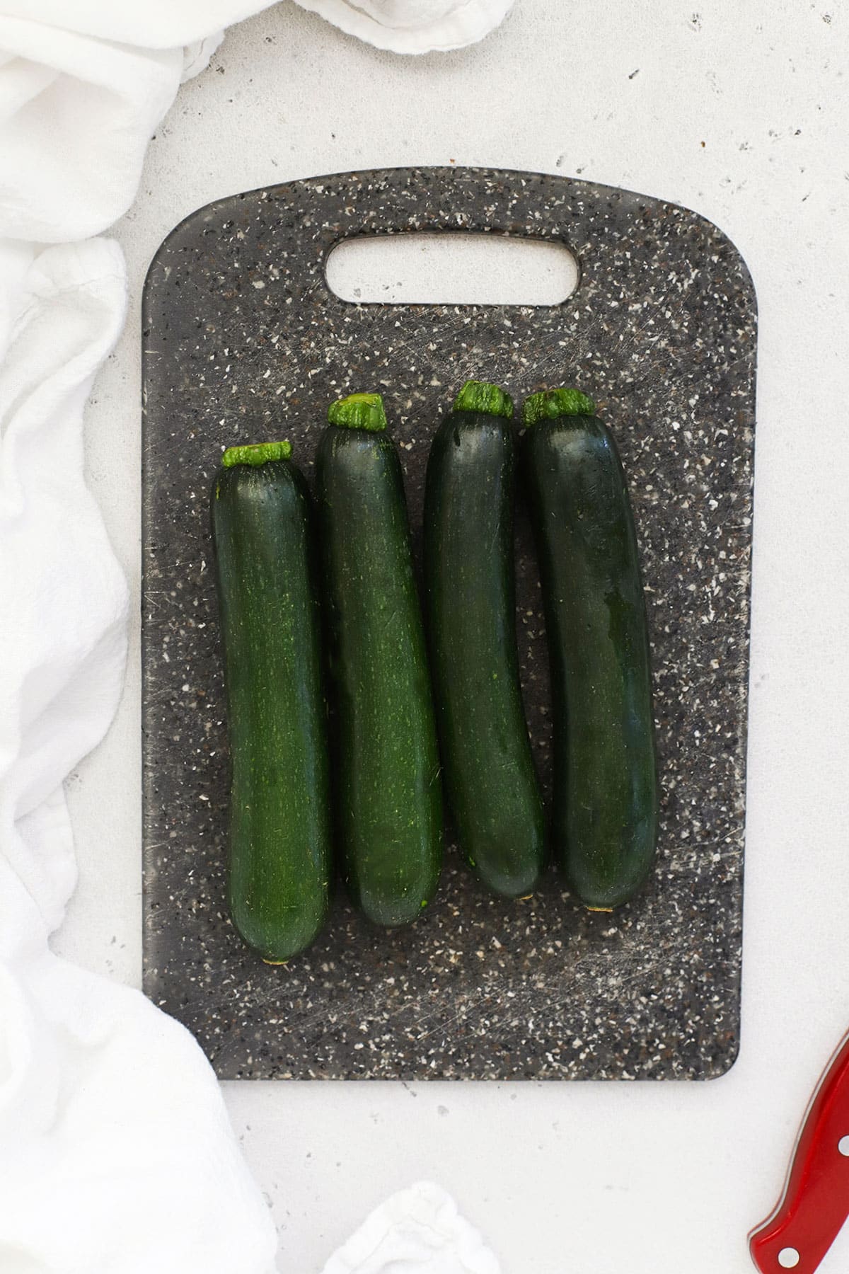 4 clean zucchini on a black cutting board