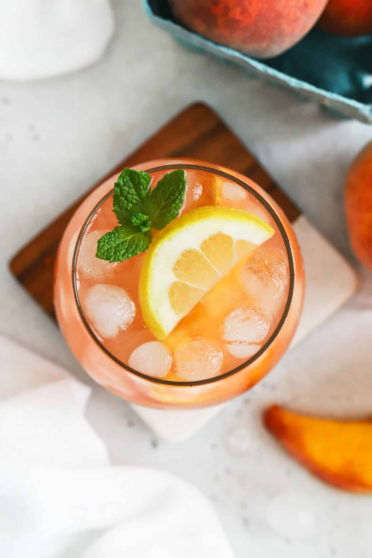 a glass of homemade peach lemonade garnished with fresh mint