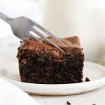 a fork cutting into a slice of gluten-free chocolate zucchini cake with chocolate frosting