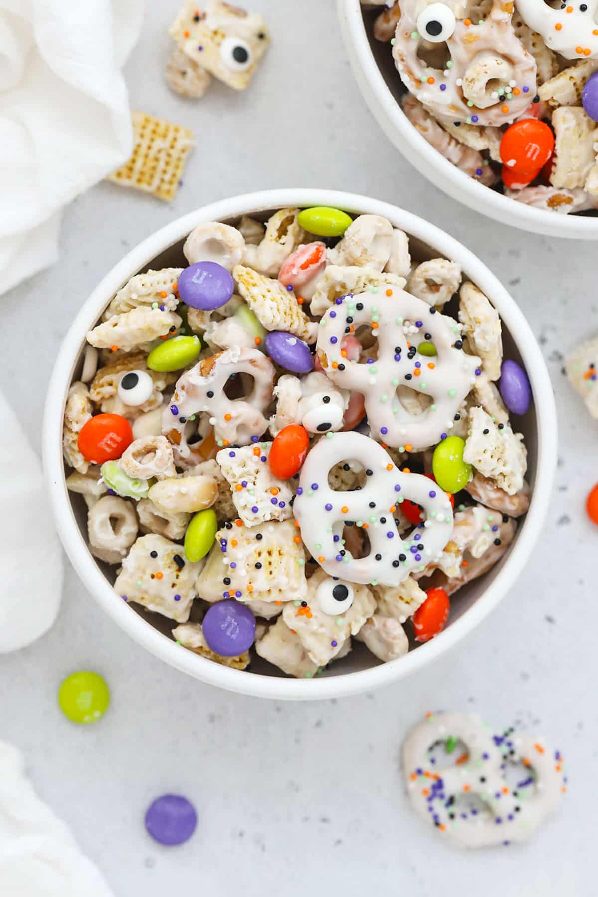 Bowls of gluten-free Halloween Chex Mix with m&ms and pretzels