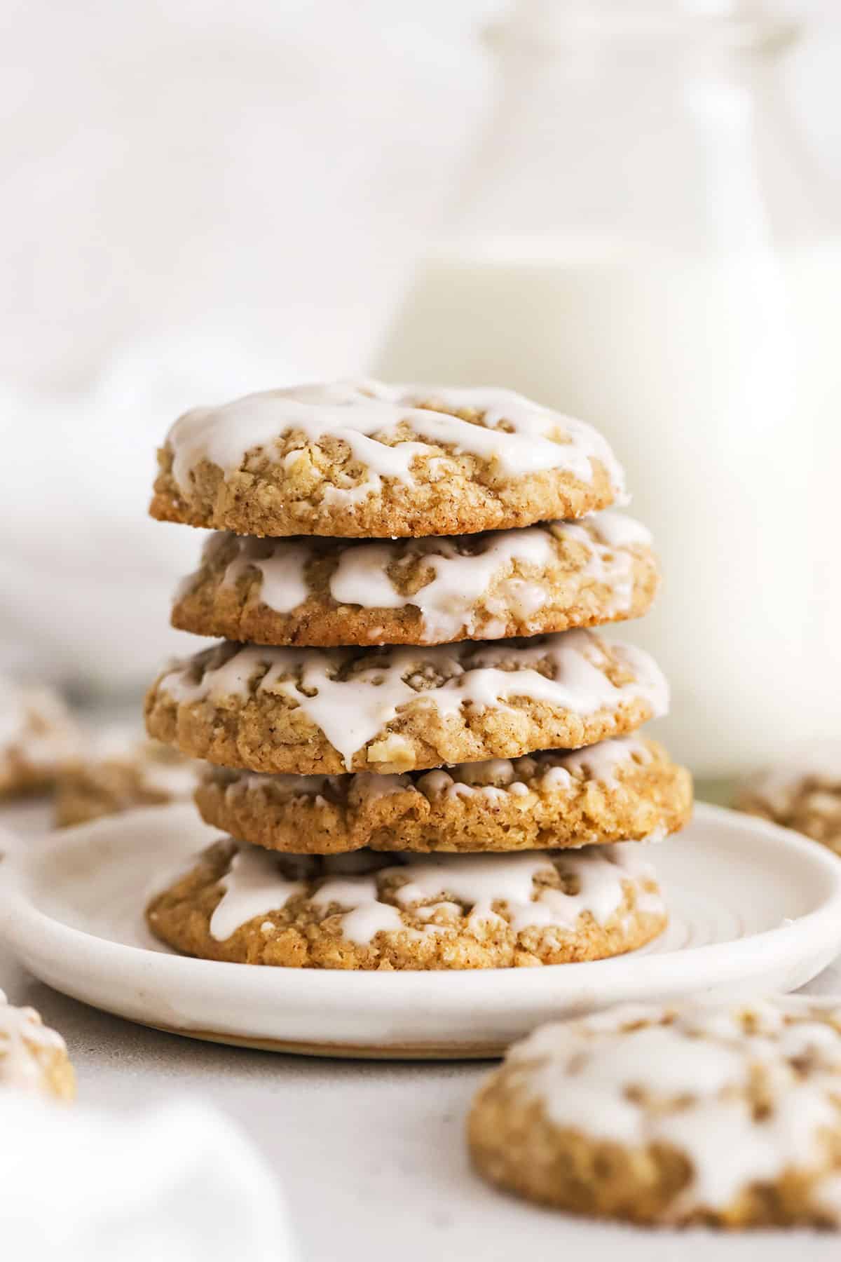 gluten-free brown butter iced oatmeal cookies stacked on a white plate