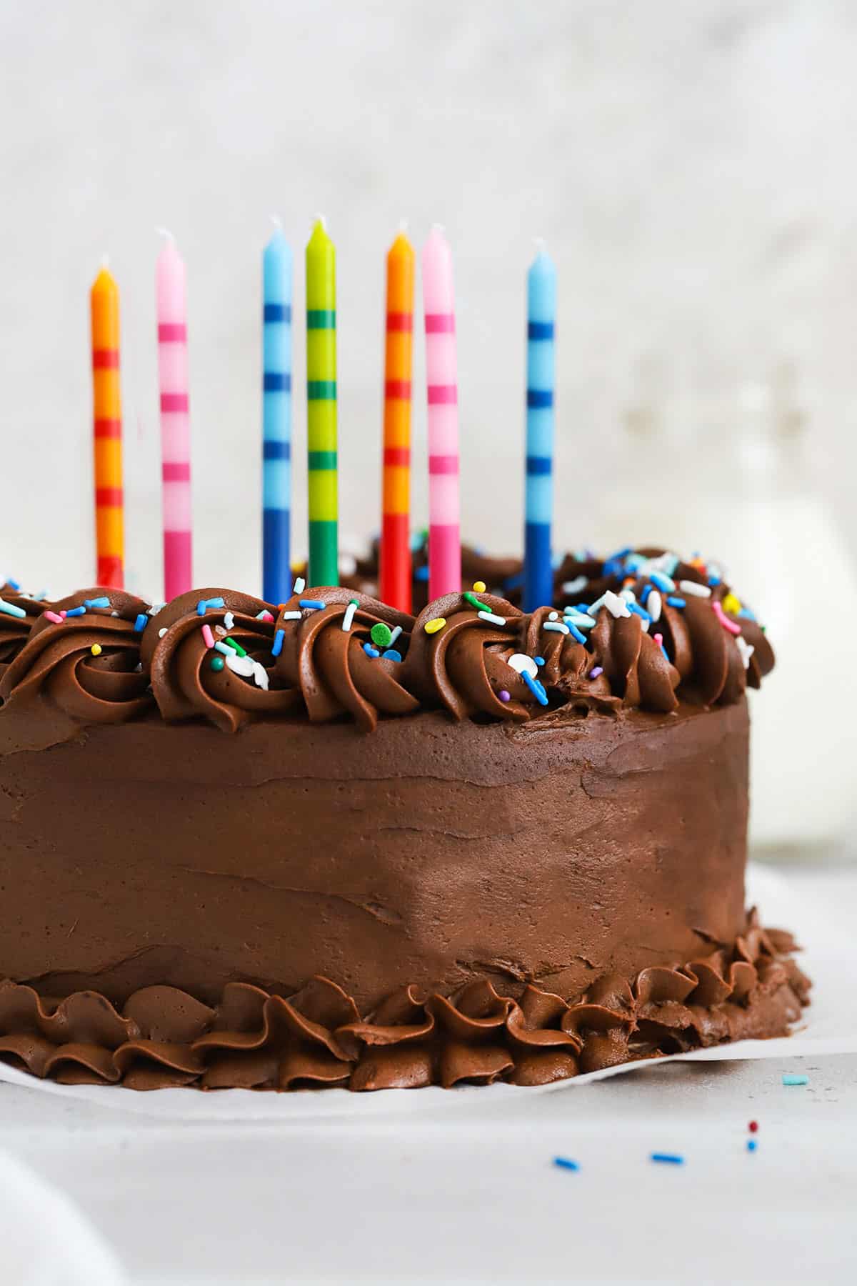 gluten-free vanilla cake with chocolate frosting, colorful sprinkles, and colorful striped birthday candles