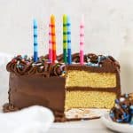 gluten-free yellow cake with chocolate frosting, colorful sprinkles, and colorful striped birthday candles