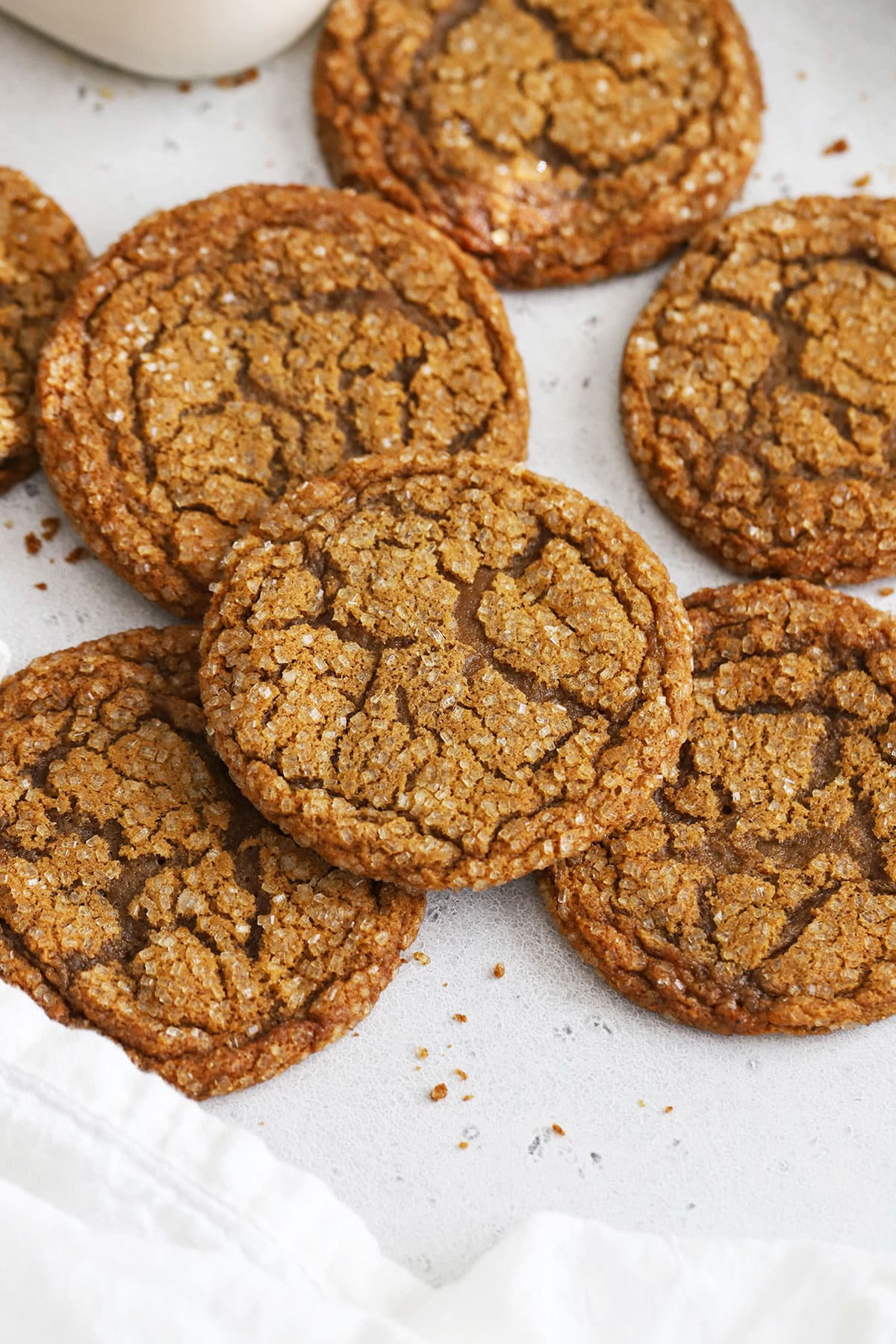 gluten-free molasses cookies stacked on a white background with a bottle of milk in the background
