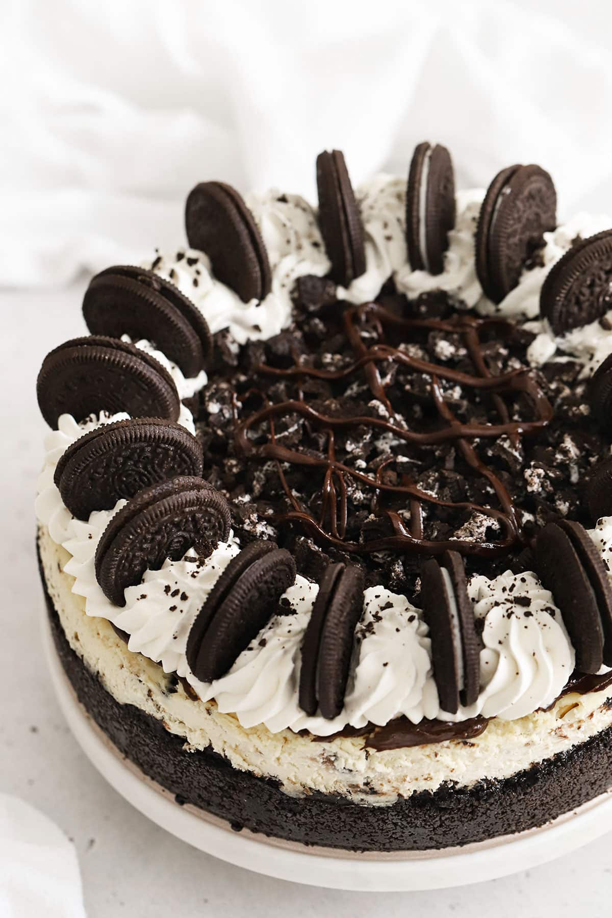 Whole Gluten-Free Oreo Cheesecake Topped With Whipped Cream Swirls, Chocolate Ganache & Oreo Cookies