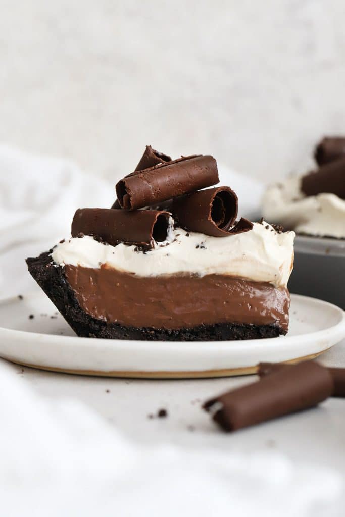 a slice of gluten-free chocolate cream pie topped with whipped cream and chocolate curls