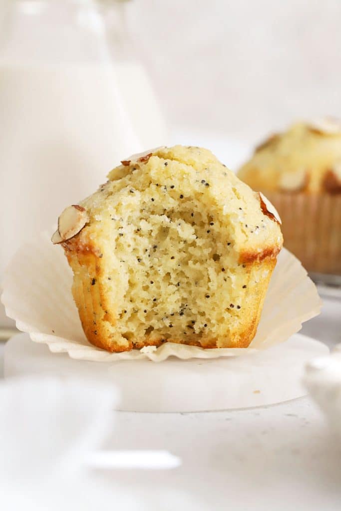 a gluten-free almond poppy seed muffin with a bite taken out of it to show the fluffy texture