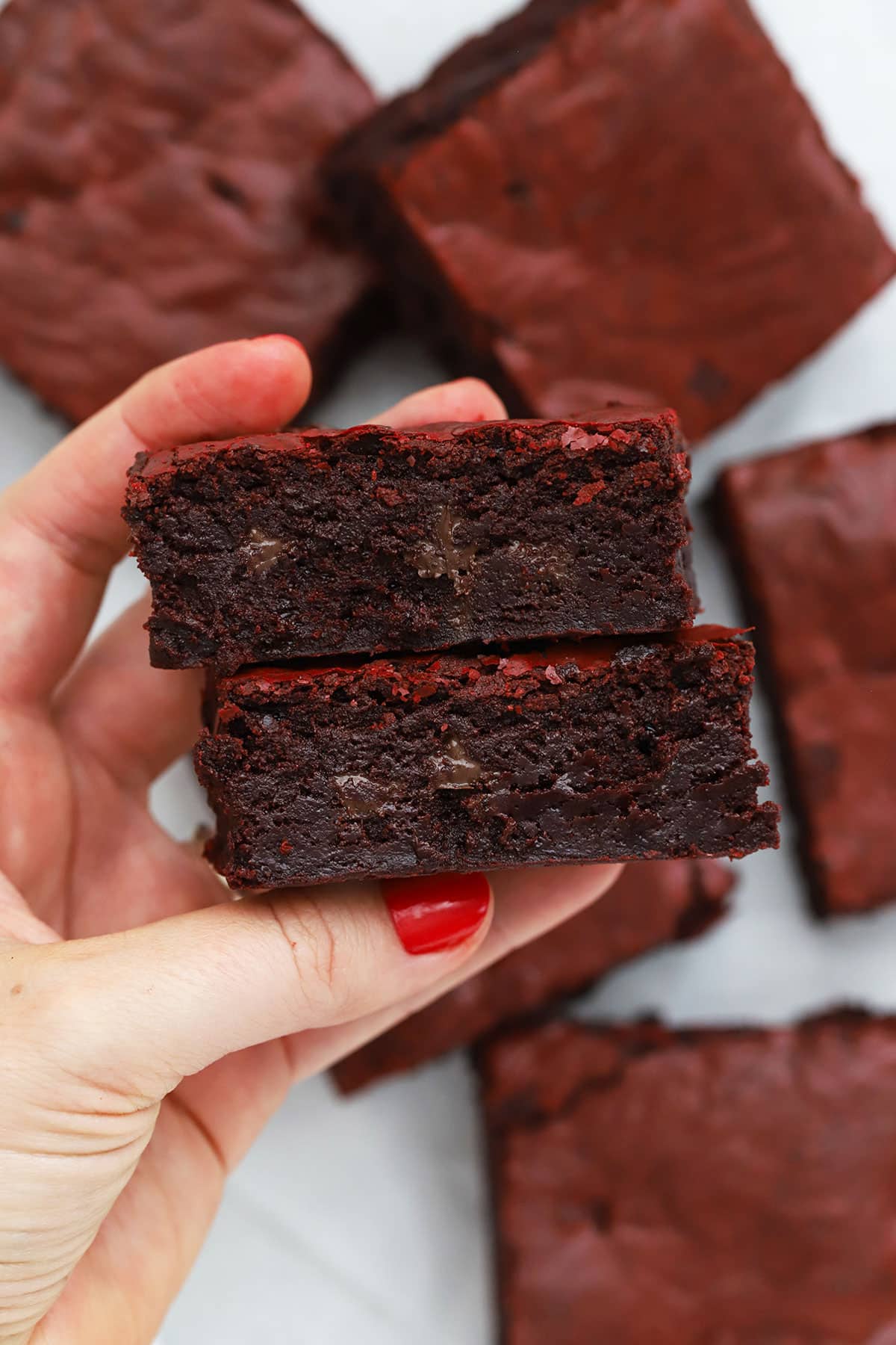hand holding two gluten-free red velvet brownies to show their fudgy texture