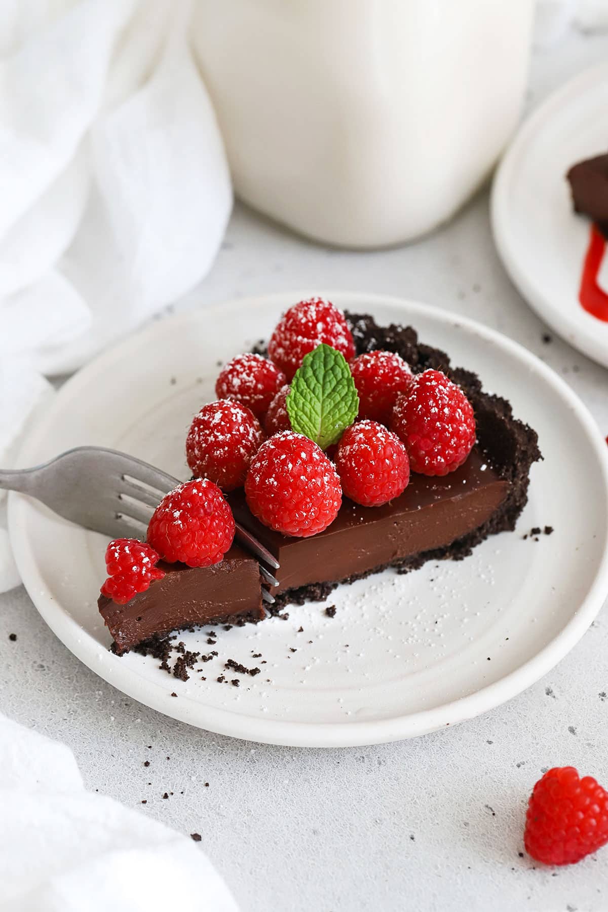 a slice of gluten-free chocolate raspberry tart on a white plate