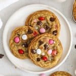 Three gluten-free Valentine's cookies with m&ms on a white plate