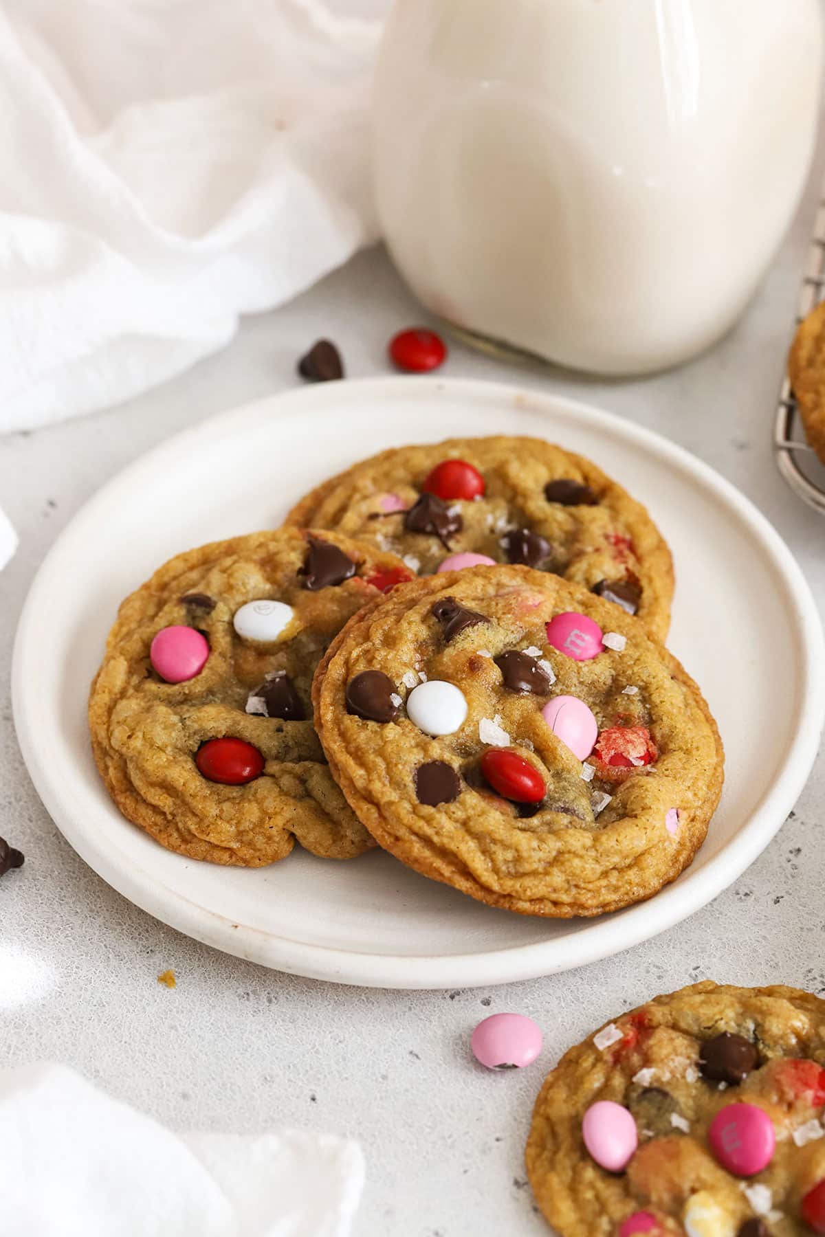 Three gluten-free Valentine's cookies with m&ms on a white plate