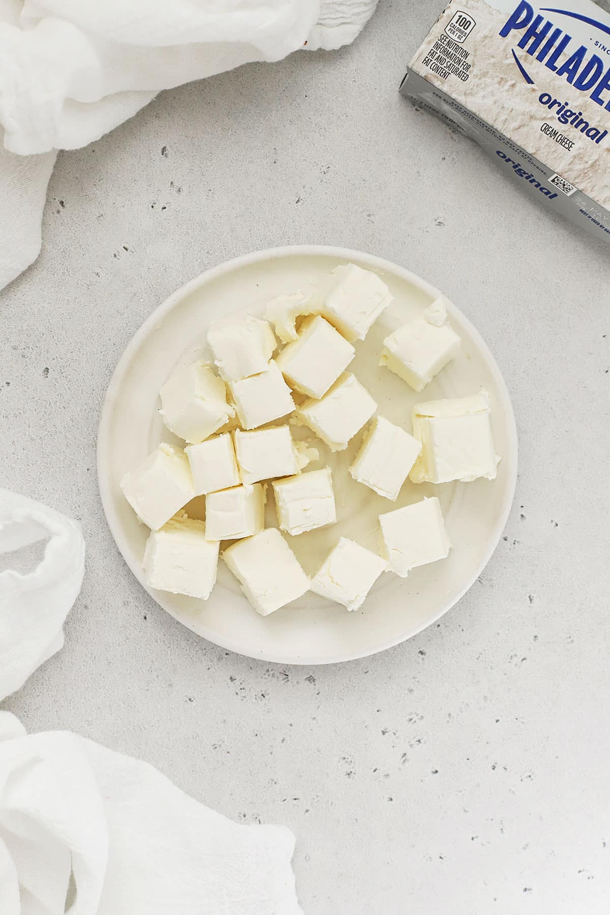 a block of cream cheese cut into small cubes on a white plate