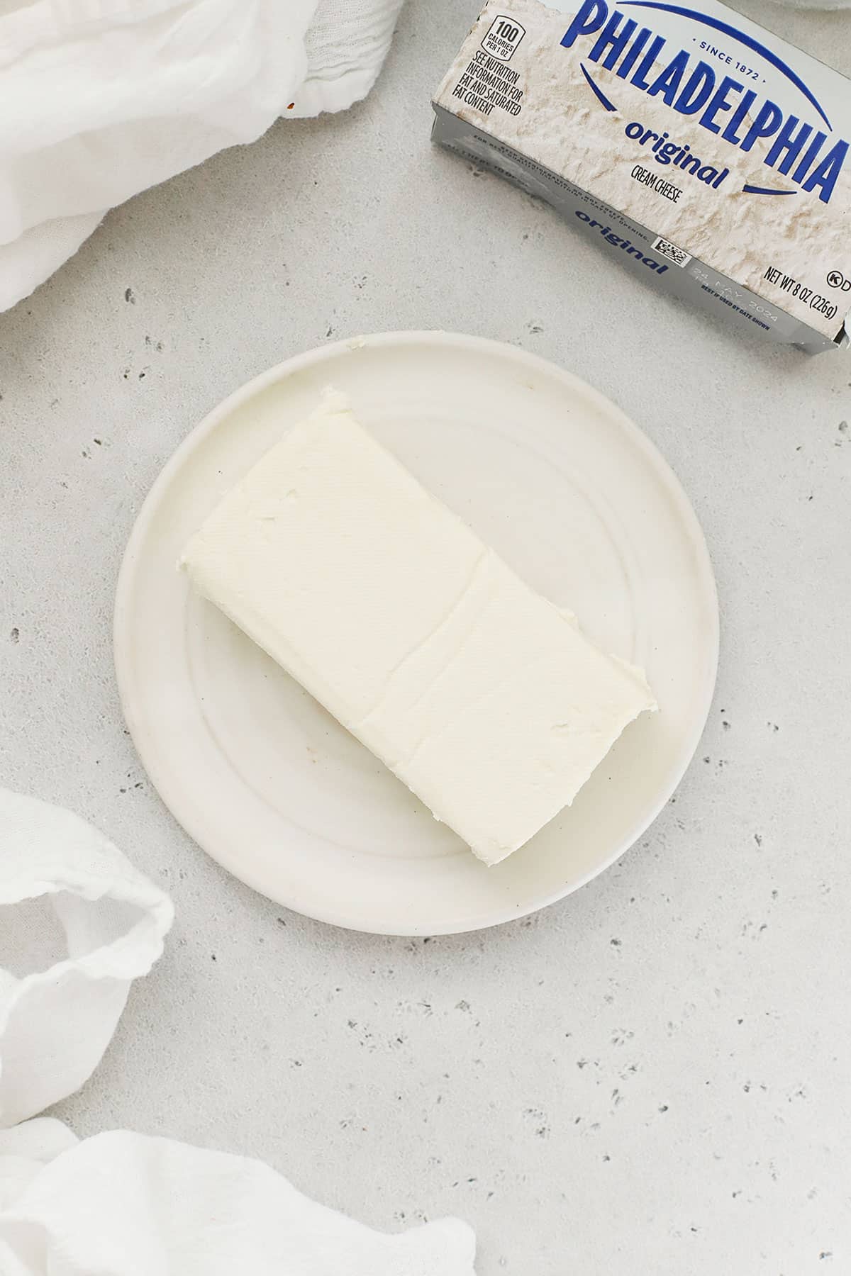 a block of cream cheese softening on a white plate