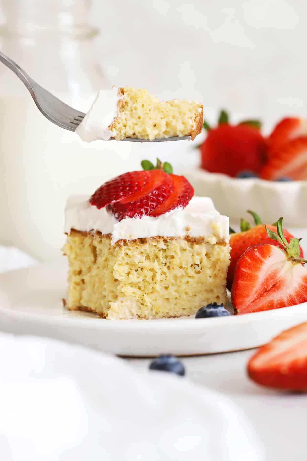 A fork getting a bite out of a slice of gluten-free tres leches cake