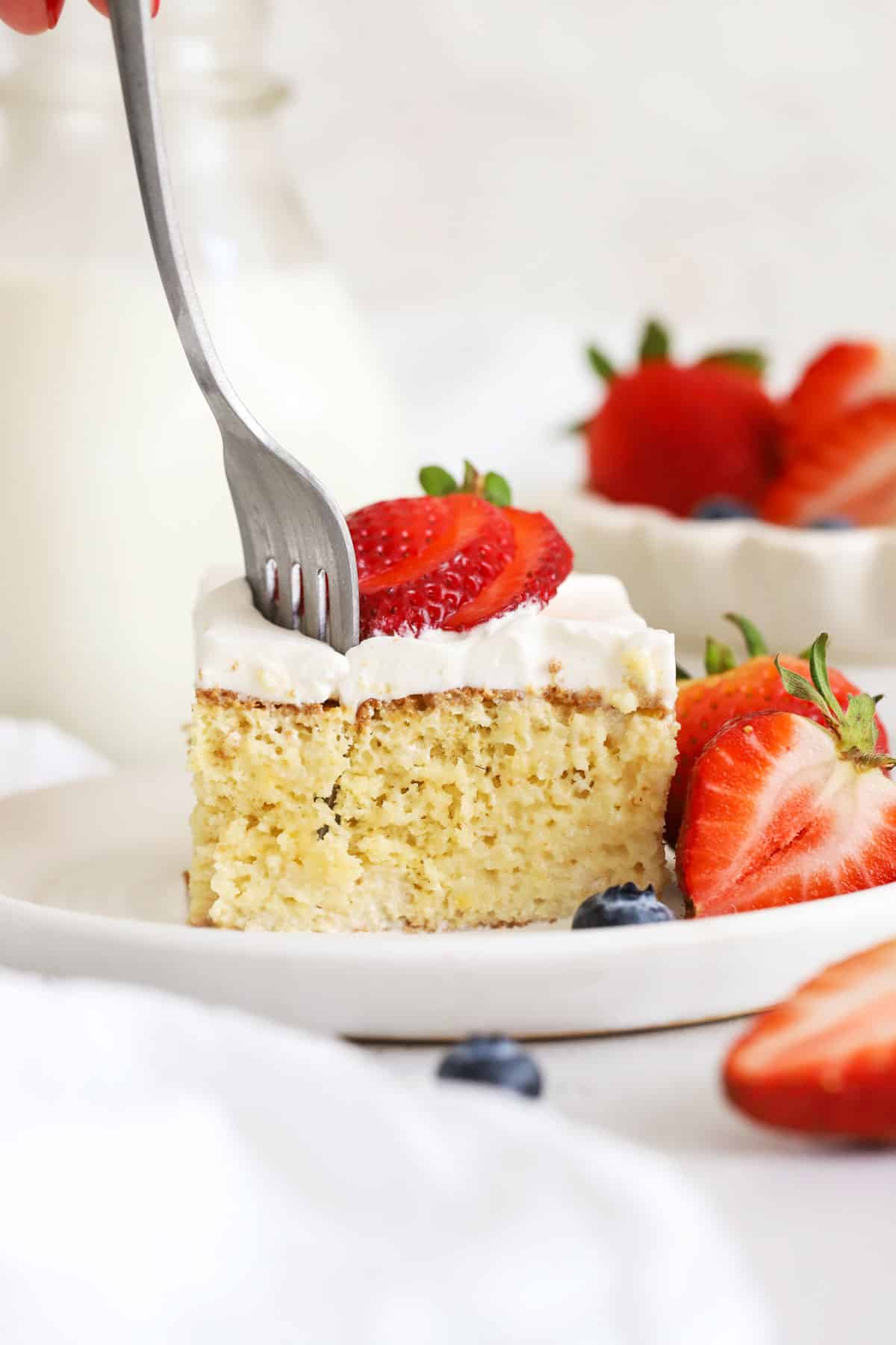 A fork getting a bite out of a slice of gluten-free tres leches cake