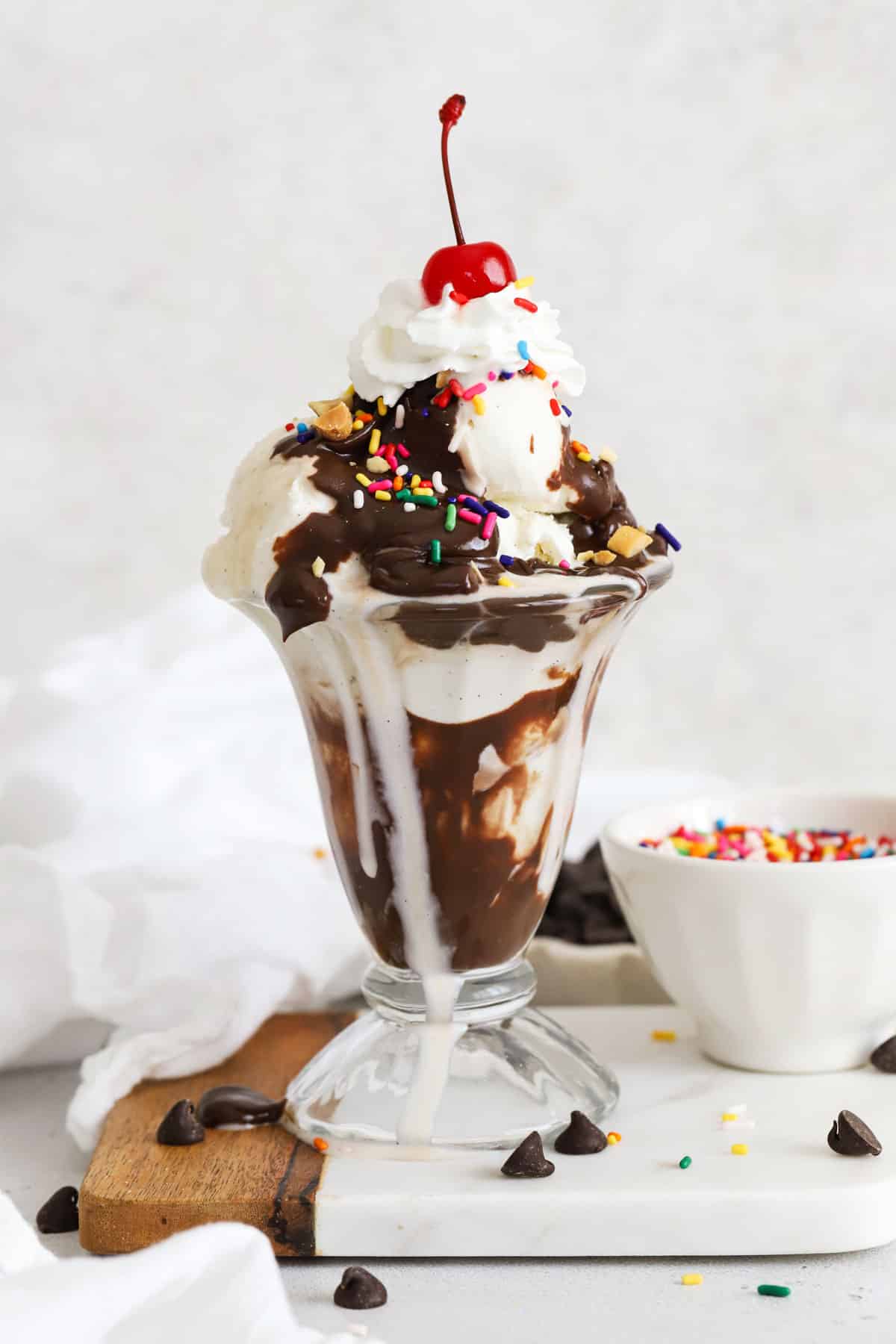 classic hot fudge sundae topped with whipped cream, sprinkles, nuts, and a maraschino cherry