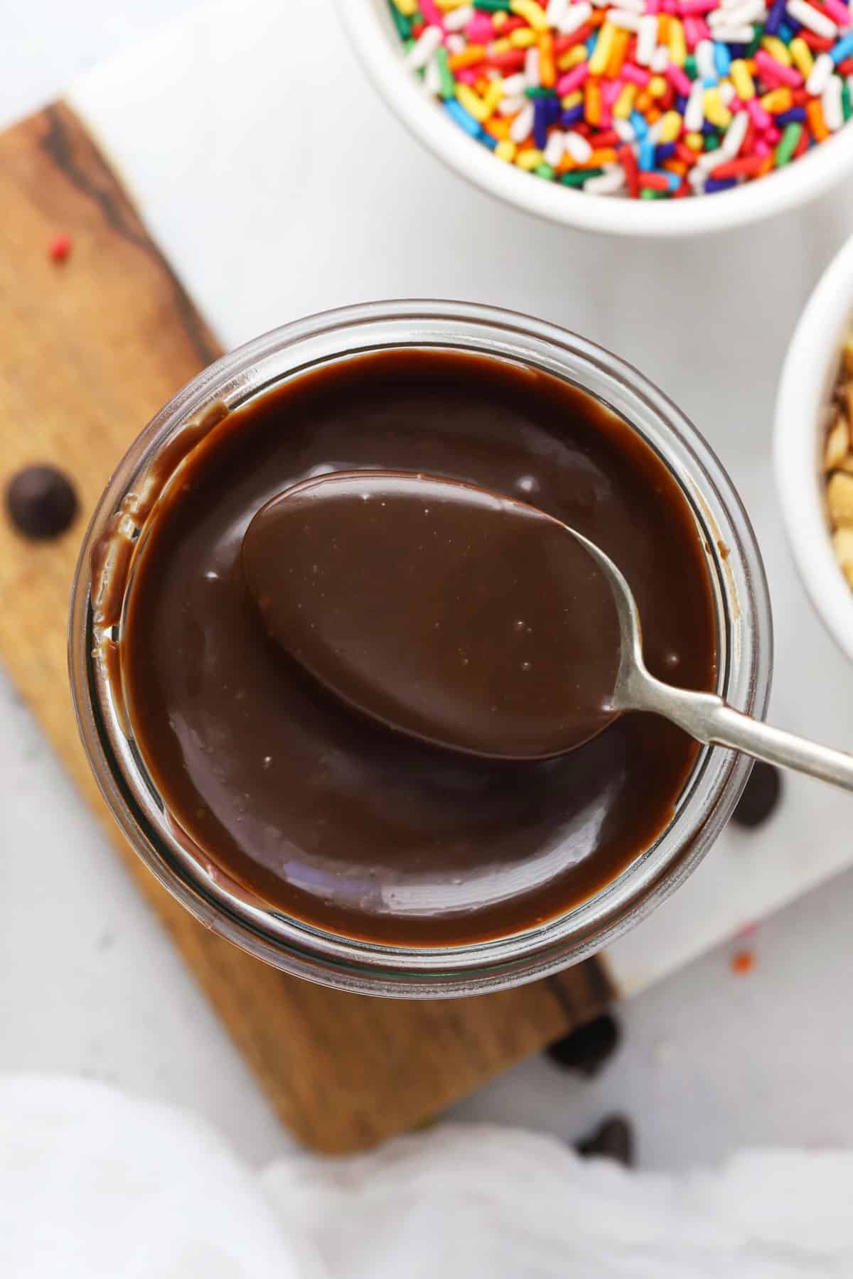 a spoon scooping homemade hot fudge sauce out of a jar