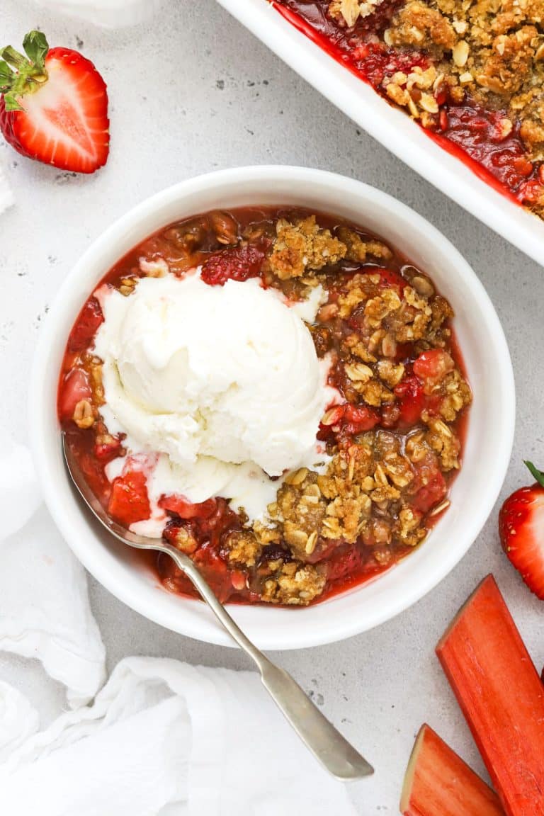 a bowl of gluten-free strawberry rhubarb crisp topped with a scoop of vanilla ice cream