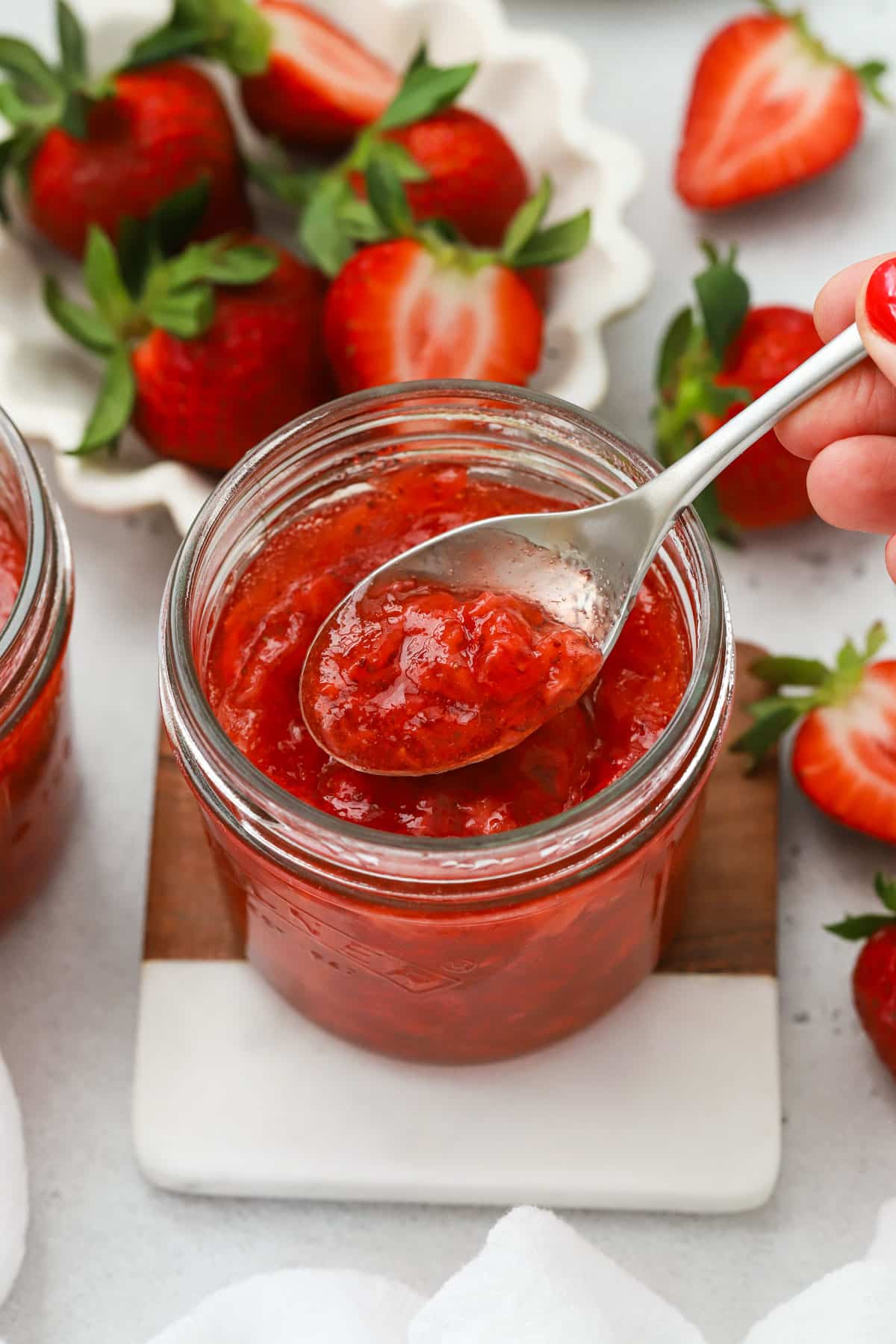 Spooning homemade strawberry freezer jam out of the jar