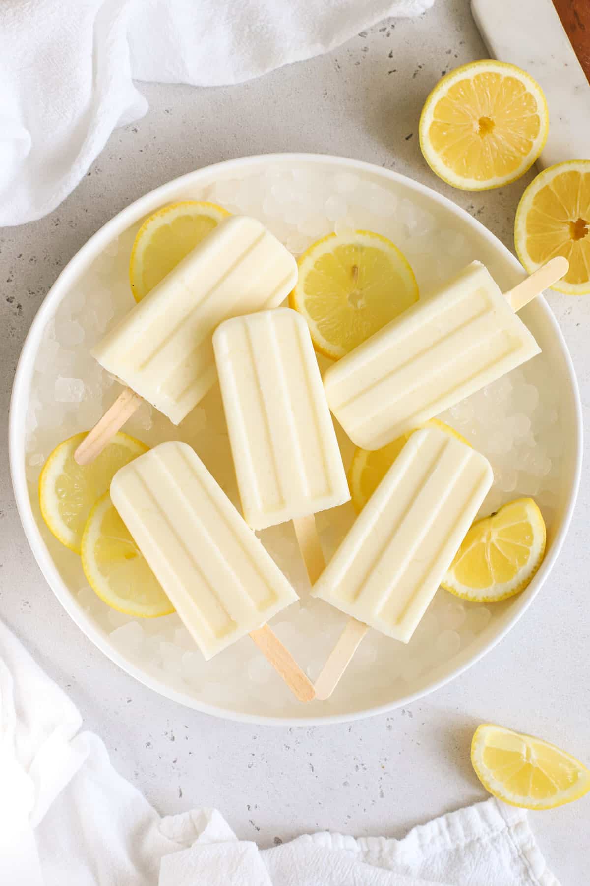 creamy lemonade popsicles on a white plate of ice