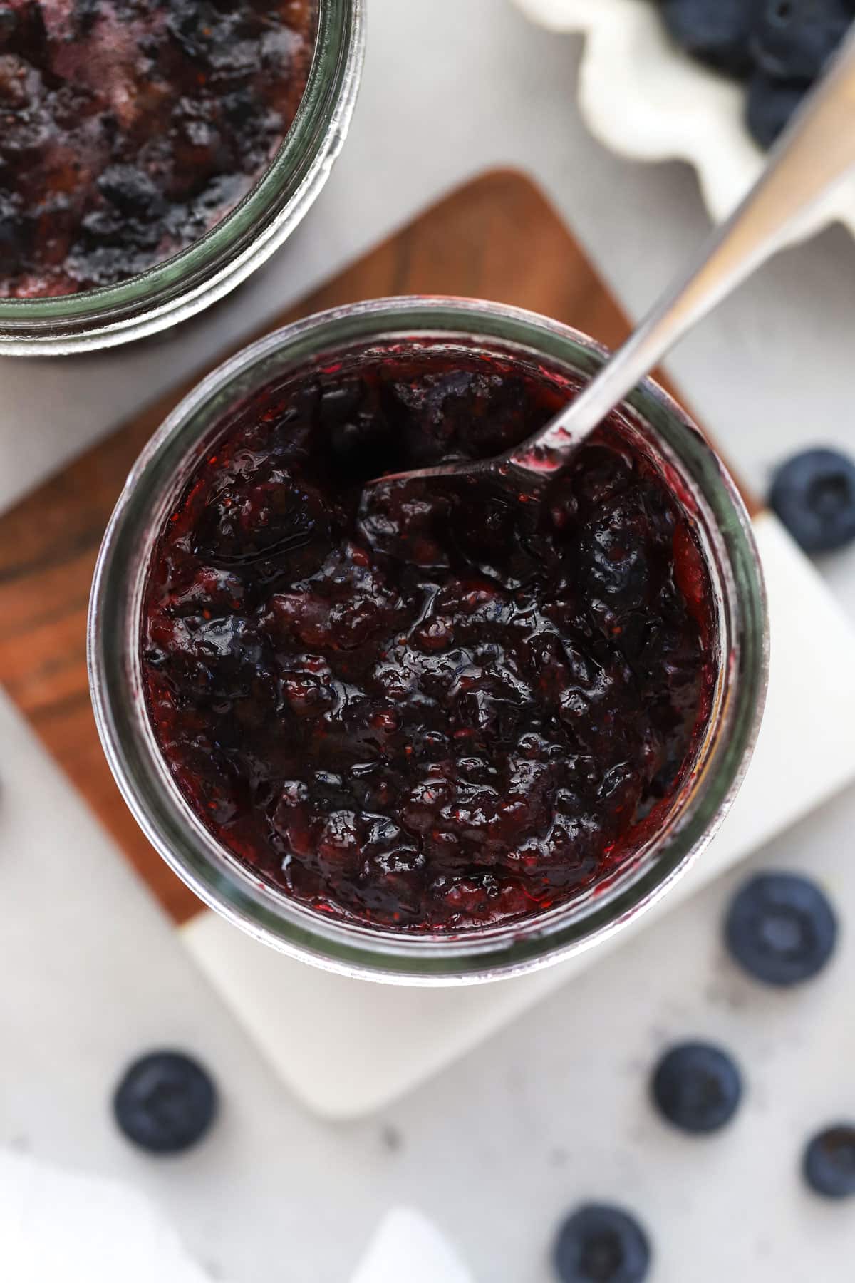 A jar of blueberry freezer jam next to a bowl of blueberries